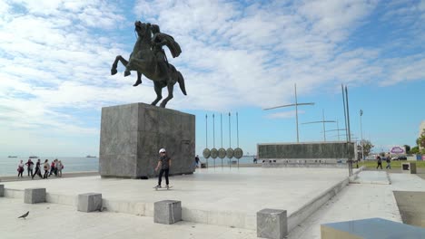 Niño-Pequeño-Monta-Monopatín-Junto-A-Alejandro-La-Gran-Estatua-En-Tesalónica