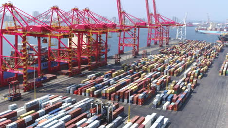 Wide-drone-tracking-shot-along-a-large-cargo-container-ship-being-loaded-by-gantry-cranes