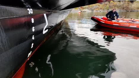 Ships-crew-standing-by-close-to-mother-vessels-hull-while-diver-is-inspecting-propellers-for-damage---Static-handheld