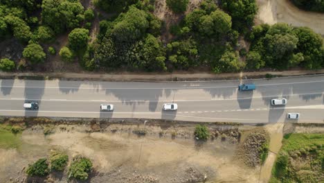 Lowering-top-down-drone-shot-of-cars-driving-on-a-rural-road-in-Spain