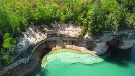 Eroded-Rock-Cliff-with-Sea-Cave-Aerial-Pan,-Pictured-Rocks-National-Lakeshore