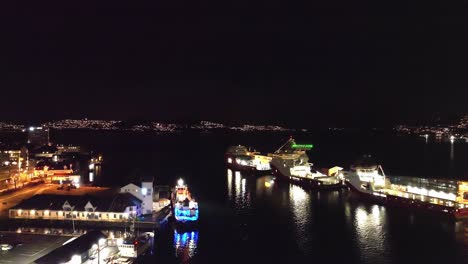 Vagen-and-byfjorden-in-Bergen-during-new-year-midnight---Ships-moored-alongside-and-random-fireworks-seen-at-Askoy-island-in-background---Norway-night-aerial