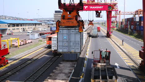 Aerial-drone-shot-of-a-saddle-crane-lifting-a-shipping-container