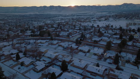 Drone-shot-of-the-sun-setting-over-the-Rocky-Mountains-in-Denver,-CO-on-a-snowy-winter-day