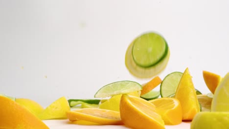 Bright-fresh-lemon,-lime-and-orange-slices-and-wedges-bouncing-on-white-counter-and-landing-in-colorful-pile