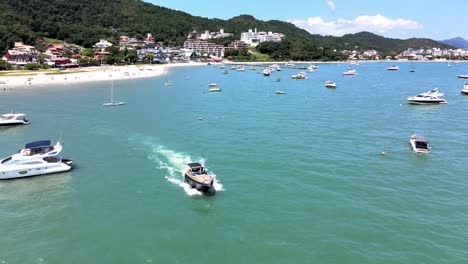 Low-flight-drone-aerial-scene-flying-over-speedboats-yachts-and-luxury-boats-with-pier-in-paradisiaca-beach-in-Jurere-internacional-florianopolis-santa-catarina