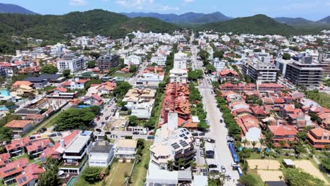 Aerial-drone-scene-of-tourist-beach-with-many-summer-houses-hotels-facing-the-sea-urban-beach-mesh-with-many-people-enjoying-the-sun-the-sand-and-the-sea-florianopolis-brazil-jurere-internacional