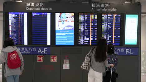 Passagiere-Schauen-Auf-Einen-Bildschirm,-Um-Zu-Sehen,-Wo-Sich-Die-Check-in-Schalter-Der-Fluggesellschaften-In-Der-Abflughalle-Des-Internationalen-Flughafens-Chek-Lap-Kok-In-Hongkong-Befinden