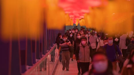 Chinesische-Pendler-Gehen-Durch-Eine-Fußgängerbrücke,-Die-Mit-Chinesischen-Roten-Laternen-Geschmückt-Ist,-Die-Von-Der-Decke-Hängen,-Um-Das-Chinesische-Neujahrsfest-In-Hongkong-Zu-Feiern