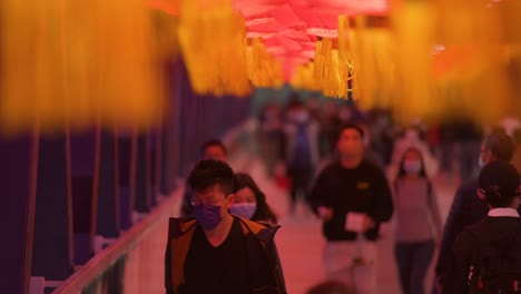Chinesische-Pendler-Gehen-Durch-Eine-Fußgängerbrücke,-Die-Mit-Chinesischen-Roten-Laternen-Geschmückt-Ist,-Die-Von-Der-Decke-Hängen,-Um-Das-Chinesische-Neujahrsfest-In-Hongkong-Zu-Feiern