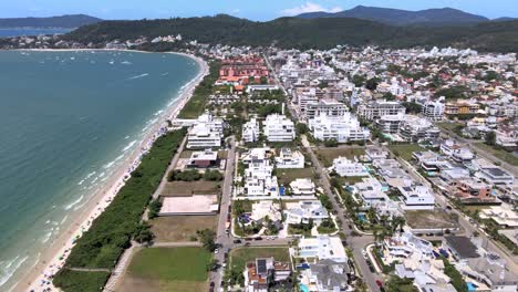 Aerial-drone-scene-of-luxurious-beach-seaside-town-in-Florianopolis-beach-town-planning-with-many-houses-and-apartments-facing-the-sea-in-Jurere-Internacional-Florianopolis