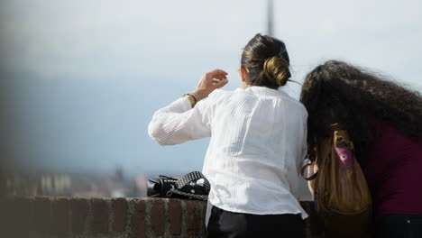Two-female-tourists-looking-out-over-unknown-skyline-in-slow-motion