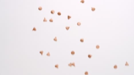Butterscotch-caramel-chips-raining-on-white-backdrop-in-slow-motion