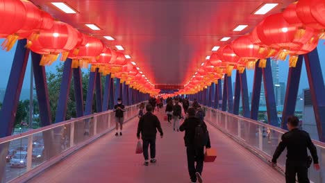 Chinesische-Fußgänger-Gehen-Durch-Eine-Fußgängerbrücke,-Die-Mit-Chinesischen-Roten-Laternen-Geschmückt-Ist,-Die-Von-Der-Decke-Hängen,-Um-Das-Chinesische-Neujahrsfest-In-Hongkong-Zu-Feiern