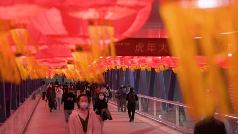 Chinesische-Fußgänger-Gehen-Durch-Eine-Fußgängerbrücke,-Die-Mit-Chinesischen-Laternen-Geschmückt-Ist,-Die-Von-Der-Decke-Hängen,-Um-Das-Chinesische-Neujahrsfest-In-Hongkong-Zu-Feiern