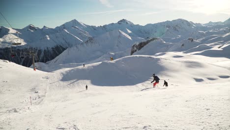 Skiers-skiing-down-a-white-clean-slope-next-to-a-ski-lift-in-the-white-snowy-Swiss-alps-on-a-sunny-winter-day