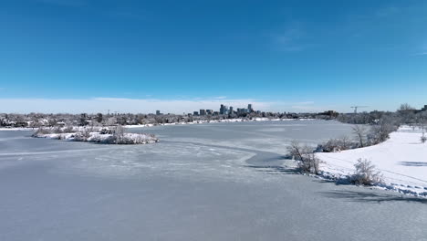 Flying-Over-a-Frozen-Sloan-Lake-to-Reveal-Denver-City-During-Winter-Storm-Aerial-Drone-Shot