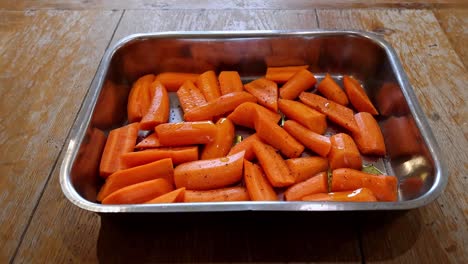 Aceite-Rociado-Sobre-Zanahorias-Peladas,-Cortadas-Y-Sazonadas-Listas-Para-Asar