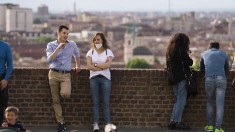 Los-Turistas-Escalofriante-Por-Pared-De-Ladrillo-Con-La-Ciudad-De-Turín,-Italia-En-Segundo-Plano.