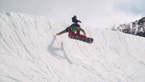 Young-Australian-Snowboarder-performs-halfpipe-maneuver-handplant-snow-spring-blue-bird-day-with-mates-at-Perisher-Front-Valley-Terrain-Park-July-2017-Jindabyne,-Australia-NSW-by-Taylor-Brant-Film