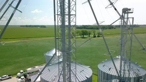 Aerial-view-rising-over-industrial-metallic-grain-silo-storage-mast-to-Arcadia-farming-countryside,-Indiana