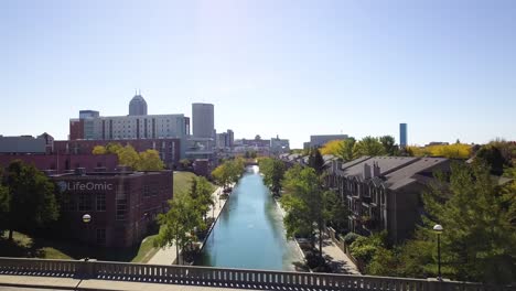 Aerial-cinematic-view-flying-over-Indianapolis-city-canal-towards-downtown-skyline