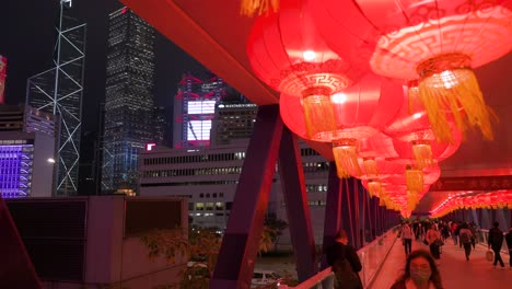 La-Gente-Camina-A-Través-De-Un-Puente-Peatonal-Decorado-Con-Linternas-Chinas-Que-Cuelgan-Del-Techo-Para-Celebrar-El-Festival-Del-Año-Nuevo-Lunar-Chino-Mientras-Se-Ve-El-Horizonte-De-Hong-Kong-En-El-Lado-Izquierdo