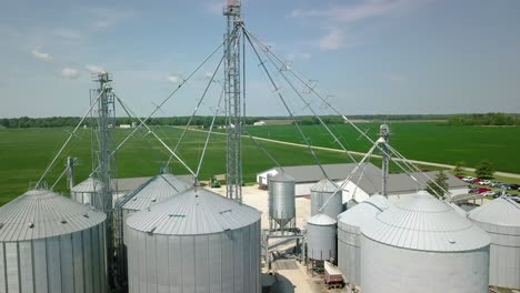 Aerial-view-flying-through-industrial-steel-mast-over-agricultural-silo-storage-on-Arcadia-farming-agribusiness-ranch,-Indiana