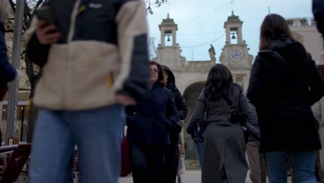 People-walk-in-Matera,-Italy-with-the-church-in-the-background