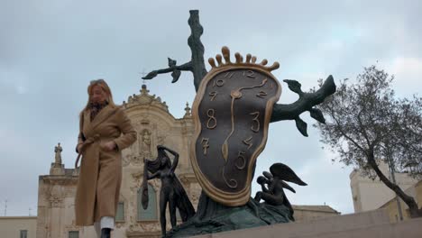 Clock-sculpture-in-Matera,-Italy-with-a-woman-posing-for-a-photo