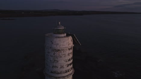 Stunning-aerial-circling-around-majestic-Lighthouse-at-evening-dusk,-shine-light