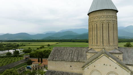 Georgian-church-tower-against-famous,-breathtaking-Caucasus-Mountains-range