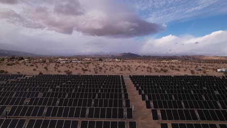 Joshua-Tree-national-park-California,-drone-fly-above-photovoltaic-farm-revealing-scenic-landscape-,-aerial-footage-of-solar-panel-in-USA