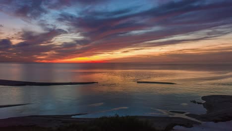 Drone-hyperlapse-of-seascape-and-coastline-against-colourful-sunset-cloudscape