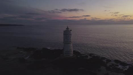Statische-Filmaufnahme-Eines-Einsamen-Offshore-Leuchtturms,-Der-In-Der-Abenddämmerung-Leuchtet