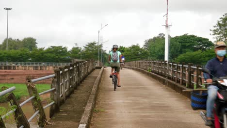 A-young-Asina-woman-exploring-Wiang-Sa-in-her-foldable-bicycle-wearing-helmet-for-safety,-Thailand,-Nan-Province