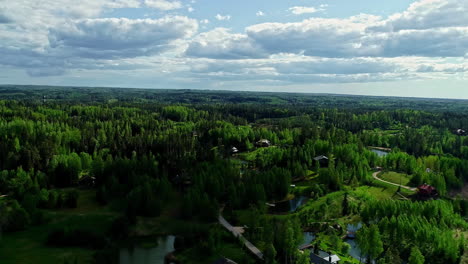 Aerial-backwards-shot-of-national-park-with-lake-and-apartments-during-sunny-day---Amatciems,Latvia