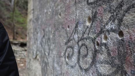 Man-touching-the-old-exterior-wall-from-an-abandoned-hospital-with-gun-shots-from-the-first-and-second-world-war-in-Sljeme,-Croatia