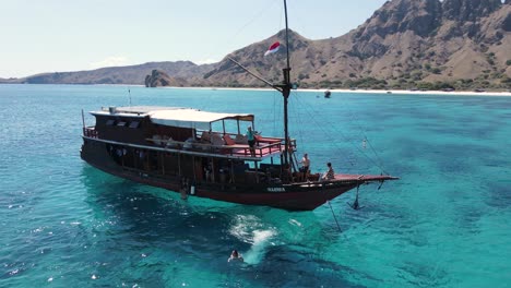 Aerial-View,-Anchored-Boats-and-People-Jumping-Into-Crystal-Clear-Water