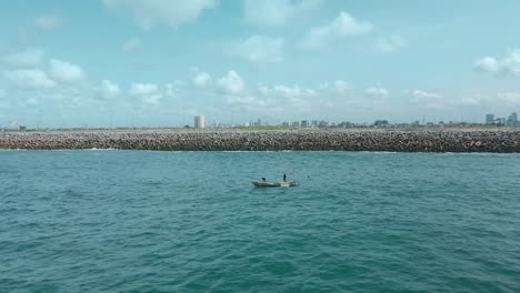 Victoria-Island-Lagos,-Nigeria---20-November-2022:-Drone-view-of-a-fisherman-on-a-fishing-boat-on-the-coastline-of-Lagos