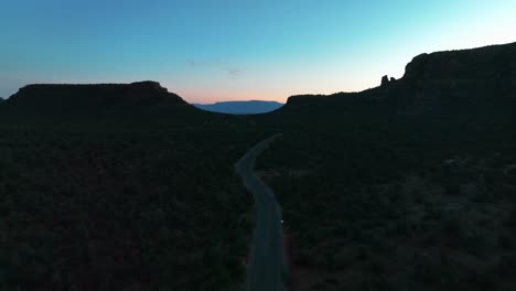 Road-Between-Vegetated-Desert-Of-Sedona,-Arizona-At-Dusk---aerial-drone-shot