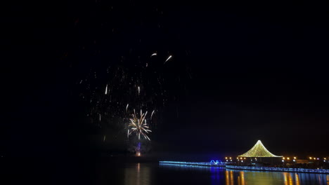 Fireworks-display,-new-years-eve,-in-marina-bay,-island-with-lights-decorated-pier