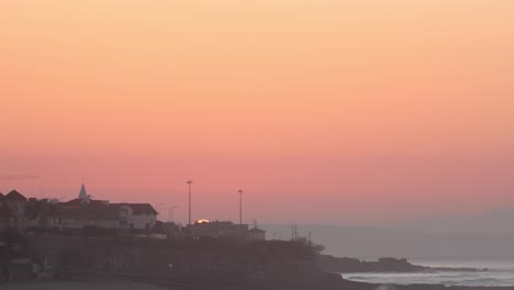 wide-view-of-the-sun-rising-from-behind-the-building-of-downtown-Lisbon,-Portugal