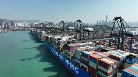 Buque-Portacontenedores-Cosco-Portugal-Amarrado-En-La-Terminal-Portuaria-De-Contenedores-En-Hong-Kong,-Disparo-Ascendente-De-Drones-De-Gran-Angular