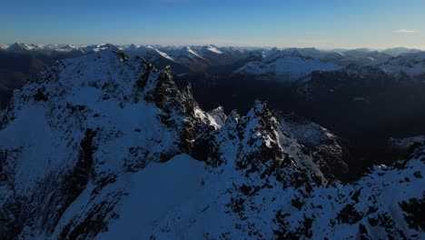 Aerial-panoramic-shot-of-snowy-mountains-during-golden-sunrise-in-Norway---Jønshornet,-Sunnmøre