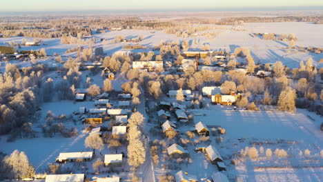 Snow-covered-village-in-Netherlands-countryside-in-winter-morning-on-golden-hour-aerial-view
