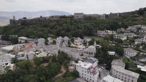 Aerial-orbiting-over-Gjirokaster-cityscape-old-downtown-with-the-Castle-in-Background,-Albania