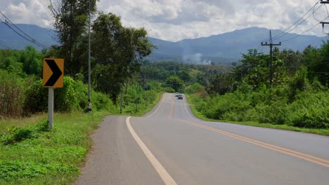 Vista-Estática-De-Pocos-Vehículos-Conduciendo-A-Través-De-Un-Hermoso-Camino-Rural-En-Un-País-Tropical-Verde-Durante-El-Día