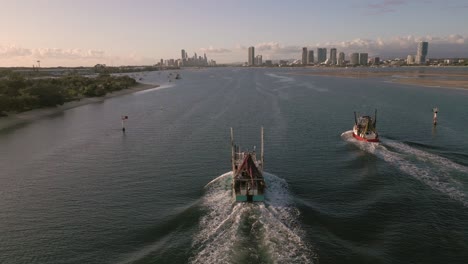 Aerial-view-over-two-fishing-trawlers-as-they-move-on-the-Broadwater-on-the-Gold-Coast-moving-towards-Surfers-Paradise,-Queensland,-Australia