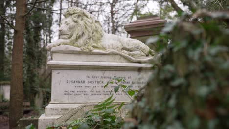 Statue-of-a-white-lion-resting-on-a-gravestone-in-forest-graveyard-on-a-cloudy-day